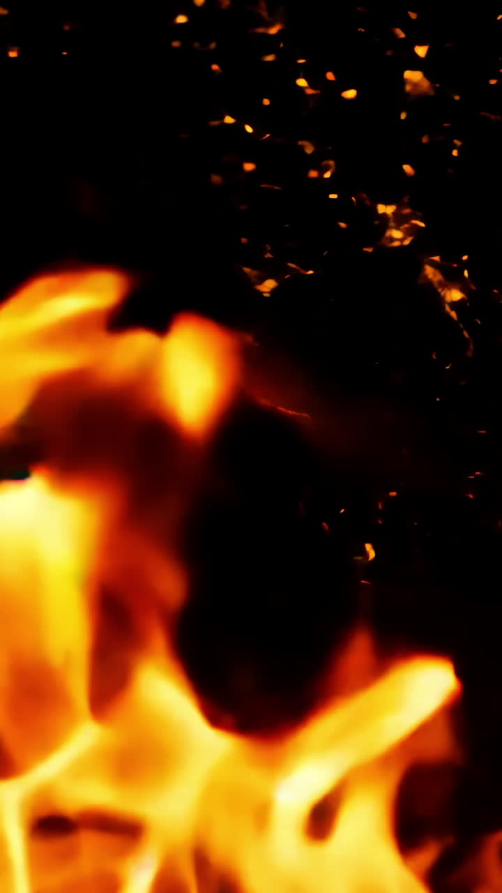 A close up of a fire with a lot of smoke and ash. The fire is orange and yellow, and the smoke is dark and billowing. Scene is intense and dramatic