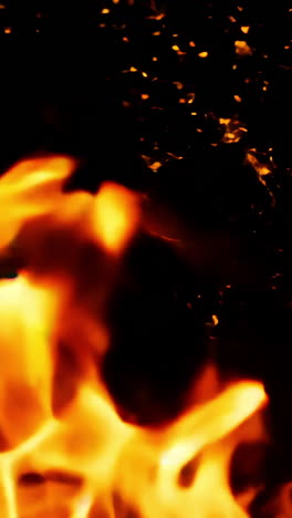 a close up of a fire with a lot of smoke and ash. the fire is orange and yellow, and the smoke is dark and billowing. scene is intense and dramatic