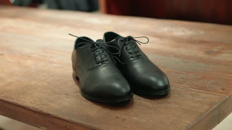 Black-leather-shoes-on-wooden-table