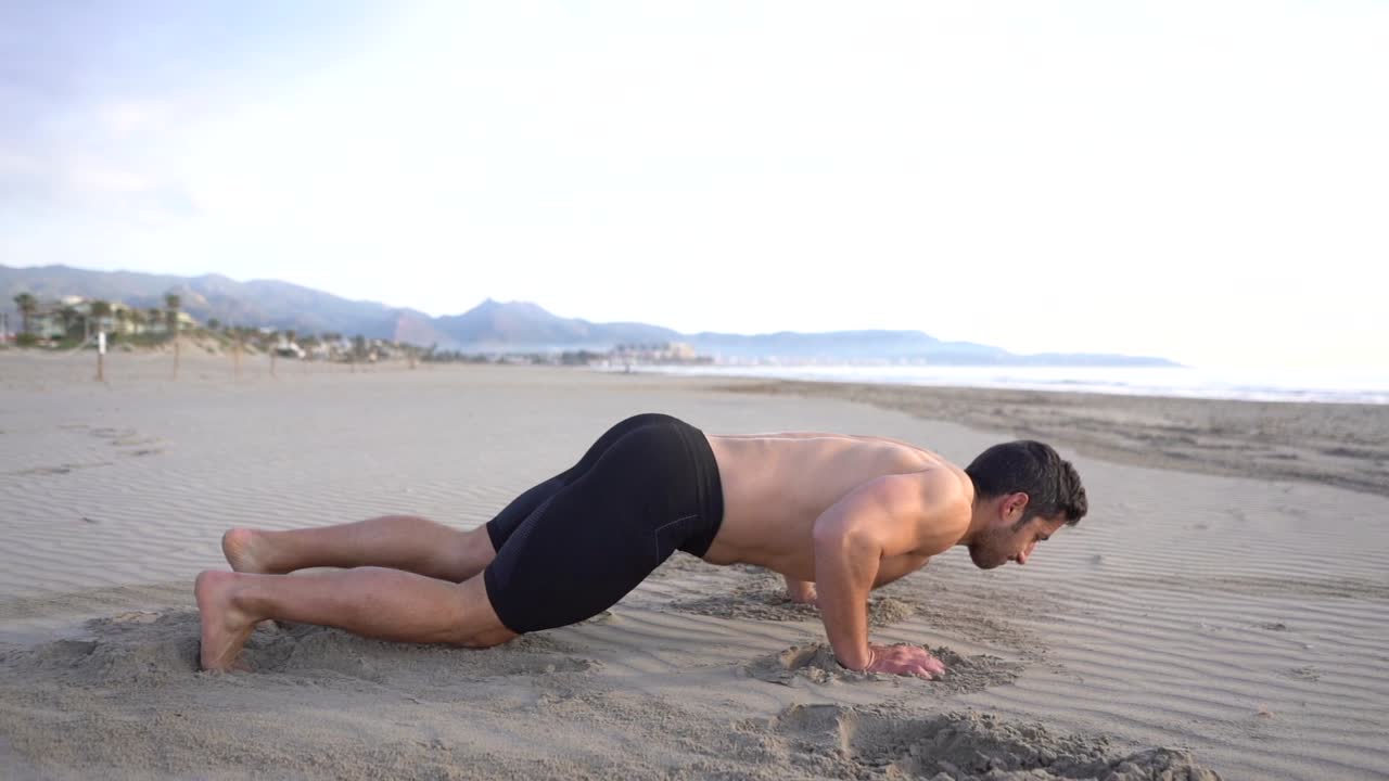 muscular man doing metabolic training with floor exercise on the beach