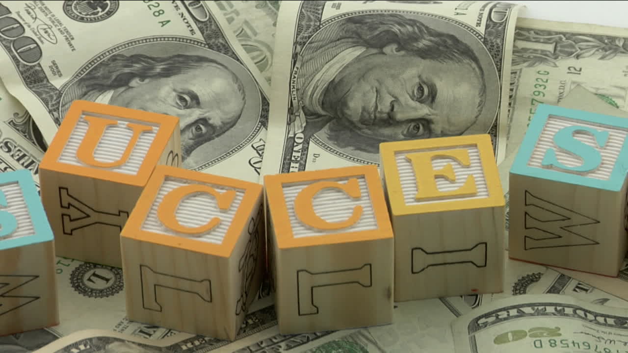 bloques de madera arreglados deletrean la palabra éxito encima de un montón de papel moneda