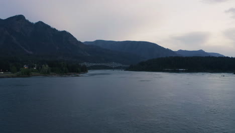 Aerial-establishing-shot-of-white-cantilever-Bridge-of-the-Gods-crossing-Columbia-River-between-Oregon-and-Washington,-PNW