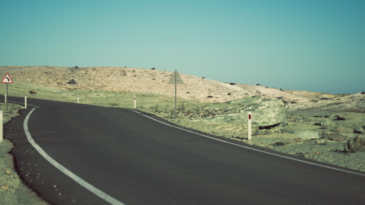 Curved road leading through the arid landscape of mongolia under blue sky