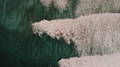 majestic ocean waves rolling towards sandy coastline, aerial top down view