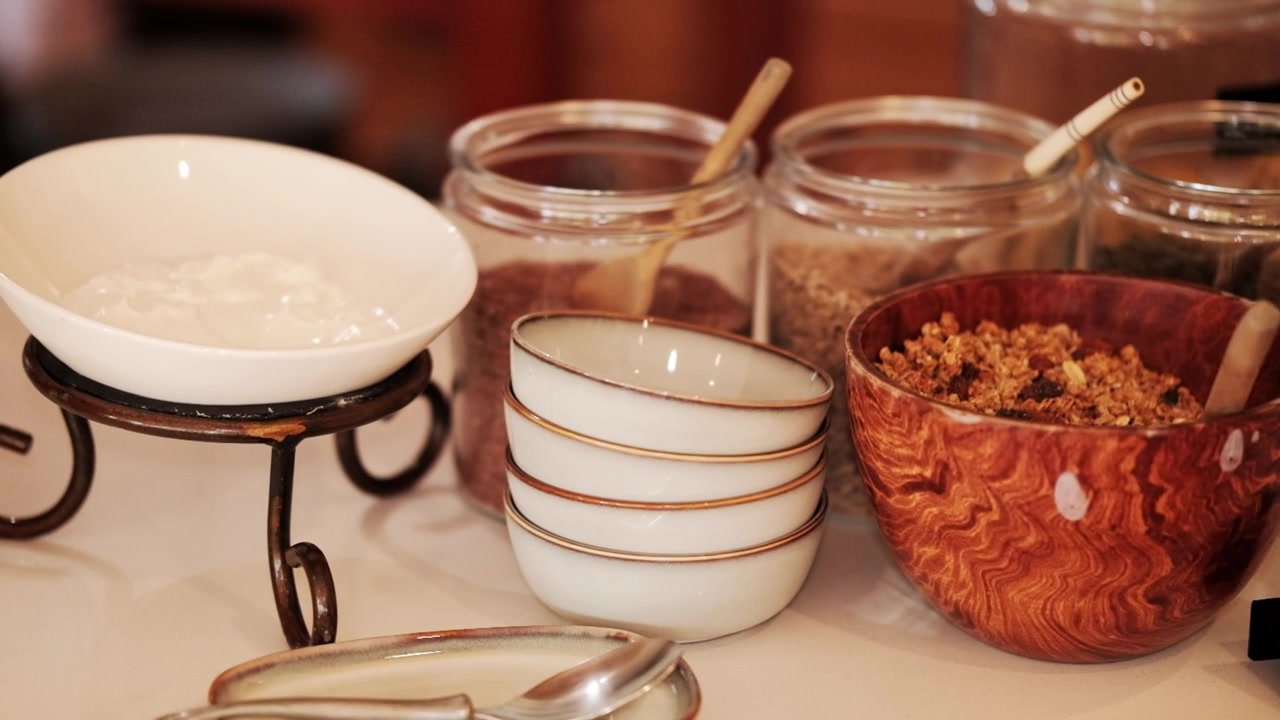A selection of yogurt, nuts, seeds and granola with breakfast bowls on the counter top of a buffet setup at a guesthouse