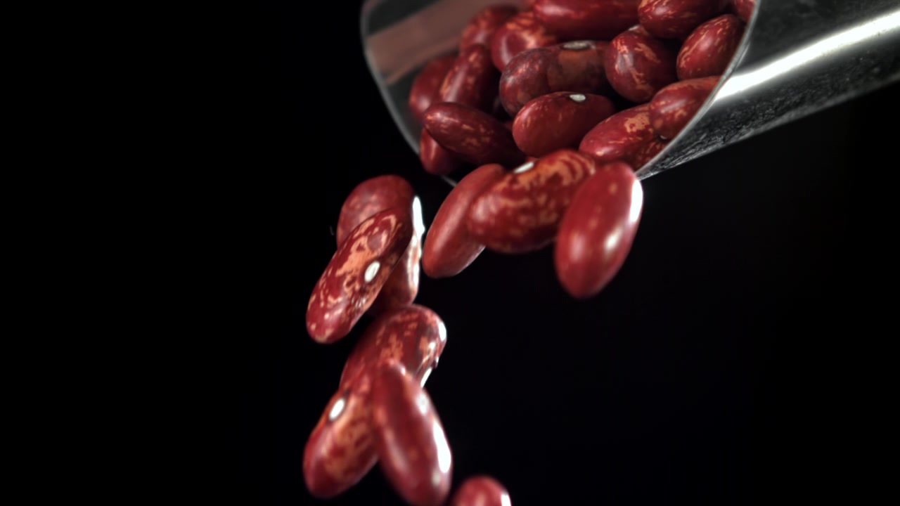 Red Beans Falling from a Metal Scoop in Slow Motion