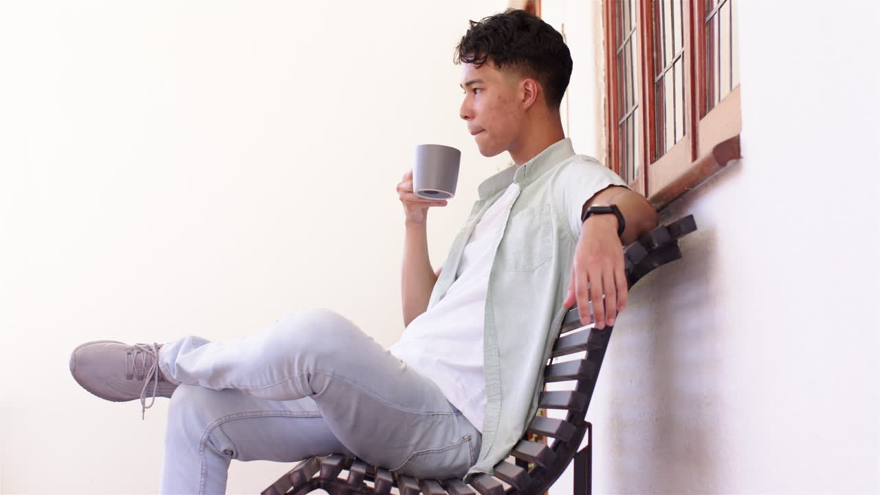 Relaxing on bench, man holding coffee mug and looking away thoughtfully