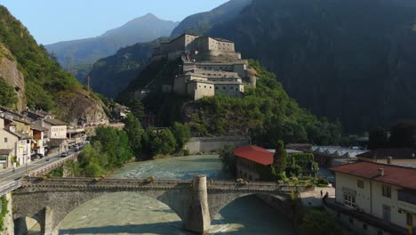 fort bard overlooks a picturesque river and bridge in the scenic aosta valley, italy