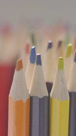 vertical video studio shot of multi-coloured pencils with hand choosing pink pencil