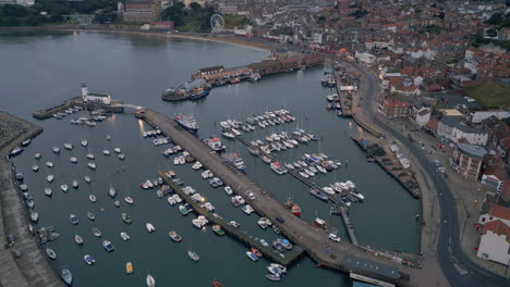 pullback establishing drone shot over scarborough harbour in low light