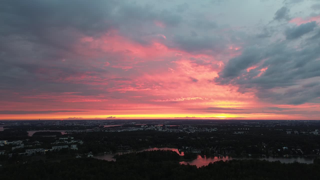 Fredfyldt luftoptagelse med drone af en levende pink og orange solnedgang over de finske øer og søområdet. Filmisk udsigt over det nordiske landskab og vandet ved skumringstid