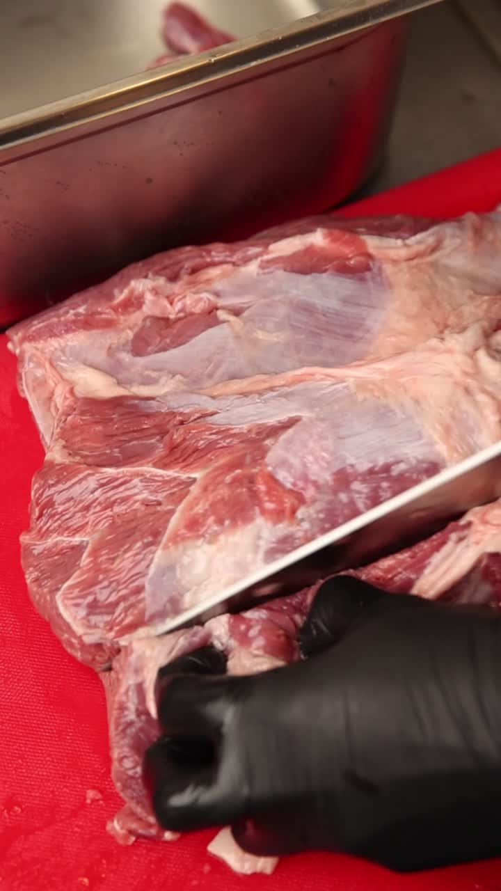 Chef cortando carne bovina crua com faca em tábua de corte vermelha