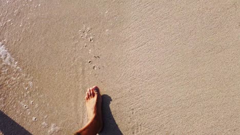 legs-of-man-walking-on-the-shore-of-the-beach