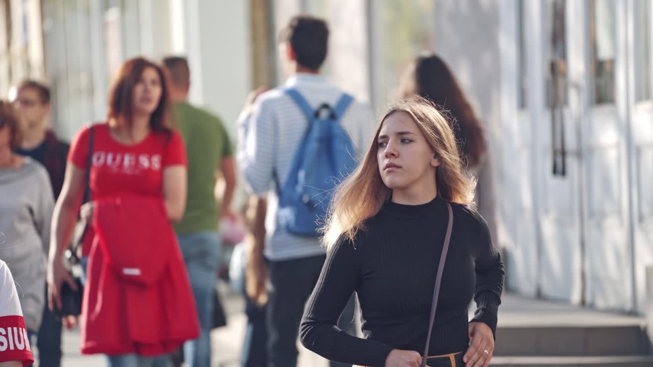 People walking along the street. Urban life scene. Crowded sidewalk with pedestrians in summer day.