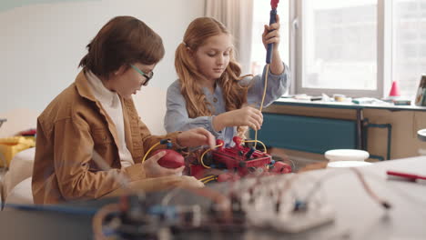 caucasian schoolgirl and schoolboy building robot