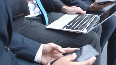 close up of unrecognizable business colleagues using laptop, smartphone, tablet outdoors