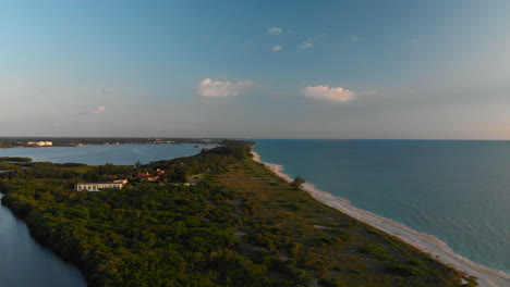 aerial, blue ocean separated from mangrove lined bay by narrow strip of land