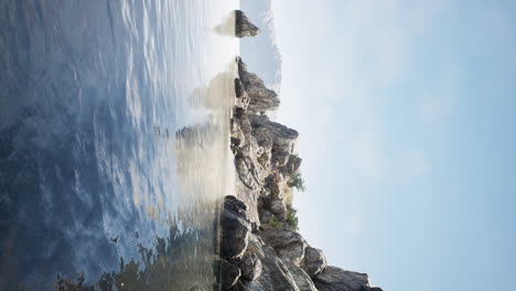 vertical video of large rock island in the middle of the sea water