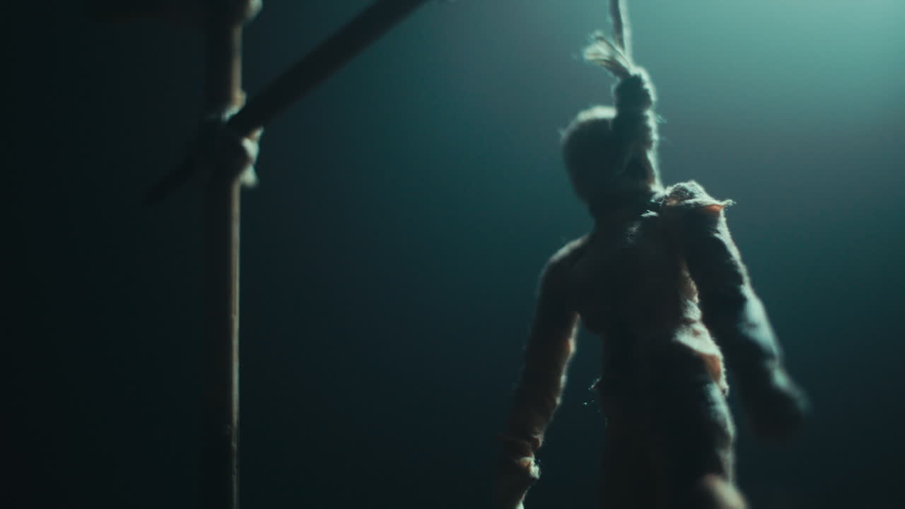 A miniature mummified doll hanging on the gallows at night