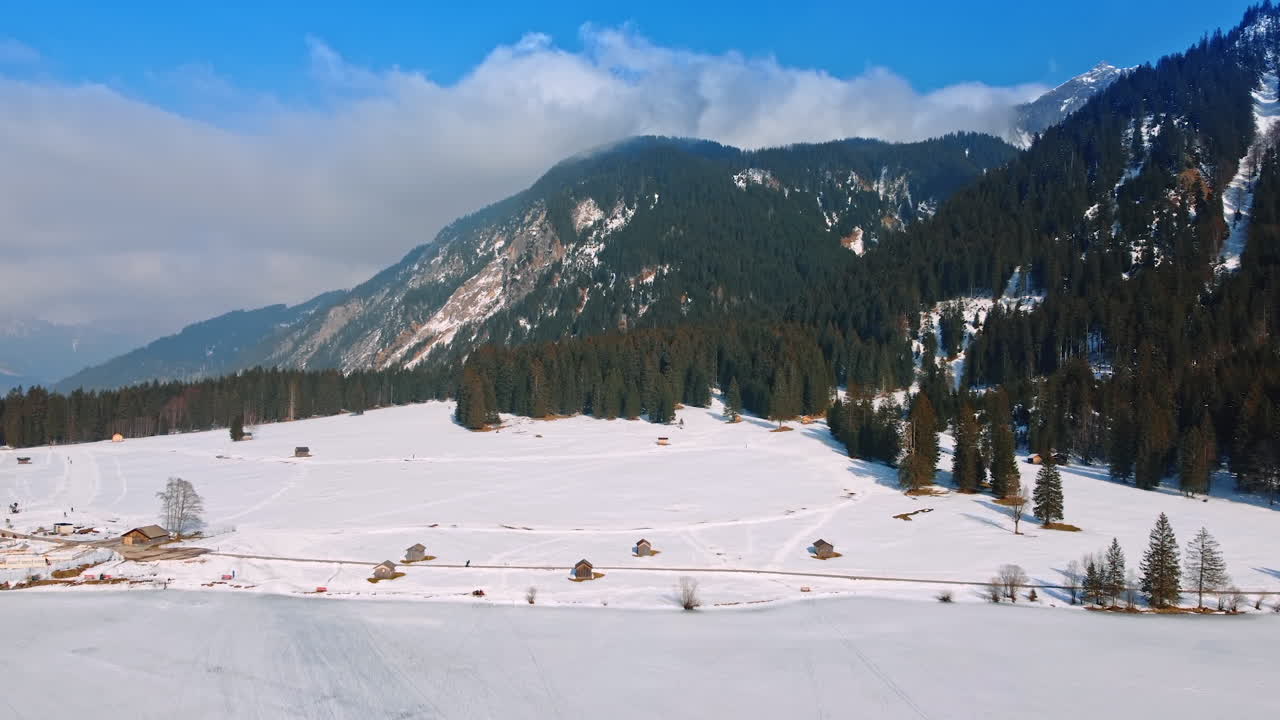 Spectacular view of Swiss Alps on sunny daytime. Top view on the several wooden huts in the snowy valley. Lichtenstein.