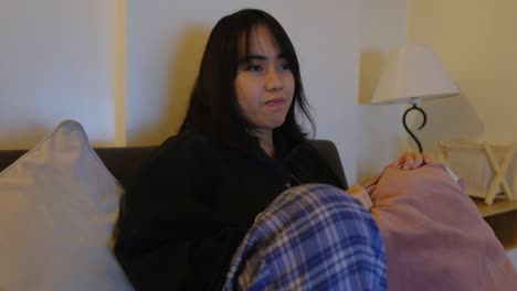 teenage woman watching television at home during nighttime