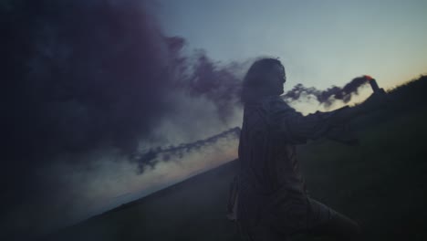 mujer sosteniendo una bomba de humo en un campo al atardecer