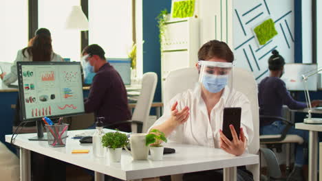 empleado con máscara facial usando videoconferencia en teléfono inteligente