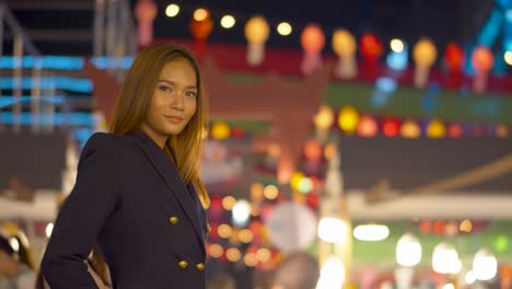 Stunning-young-woman-smiles-at-the-camera-under-the-bright-lights-of-the-city