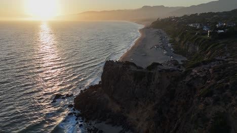 vista aérea: costa del océano puesta de sol dorada en la playa de malibu, california