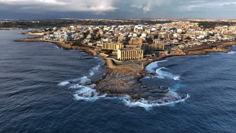 Drone-shot-landscape-view-of-Abandoned-Jerma-Palace-Hotel-in-Marsaskala,-sunrise-time,-Malta