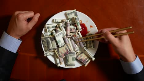 hands of a businessman with chopsticks and dollar rolls. eating dollars. 4k.