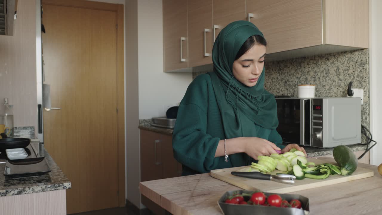 Woman wearing hijab cooking vegetables in the kitchen