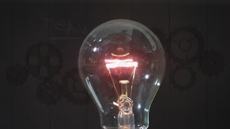 animation of bulb lightening over brown background with gears