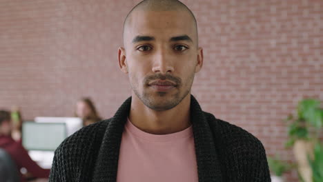 portrait of handsome young mixed race man in contemporary office workspace looking serious pensive at camera