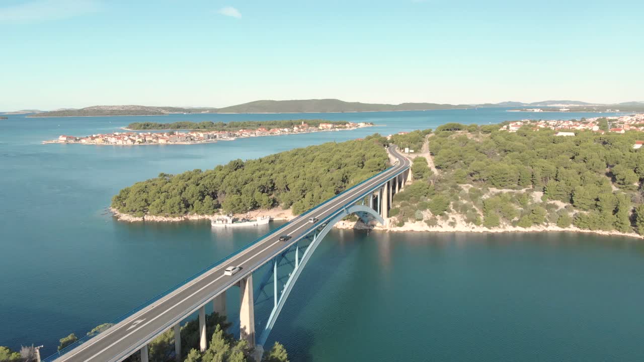Aerial spectacular view of a concrete suspension bridge between two island on Adriatic sea with car traffic and wild clear nature