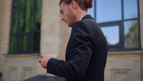 hombre enfocado usando la tableta mientras camina trabajando