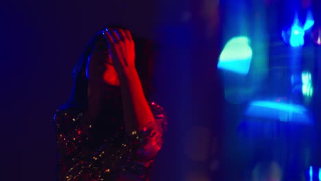 close up of woman having fun dancing in disco nightclub or bar shot with tinsel in foreground 3