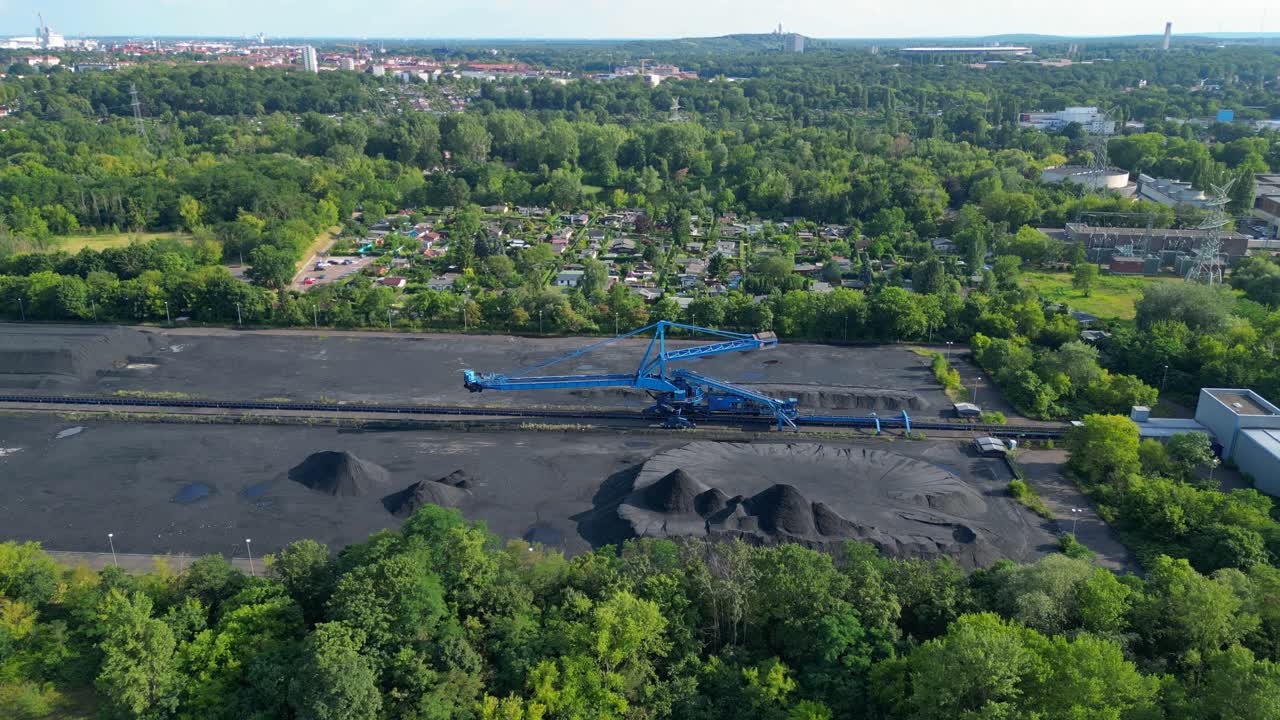Spreader reclaiming coal Excavator at a coal terminal near residential area. Majestic aerial view flight drone shot from above