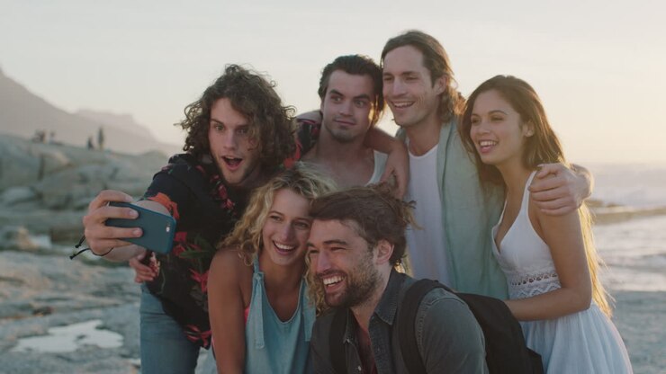 um grupo feliz de amigos a tirar uma selfie na praia.