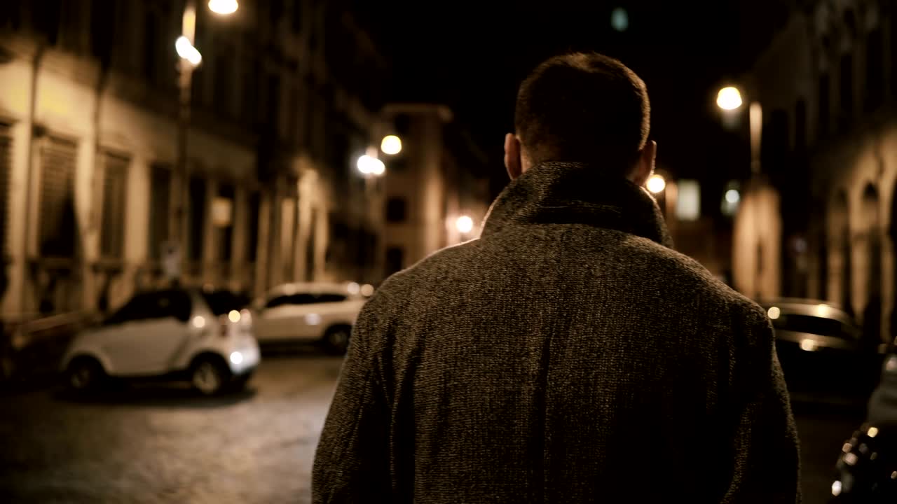 어두운 거리를 통해 늦은 밤에 는 젊은 세련된 남자의 뒷면, 혼자 저녁에 가는