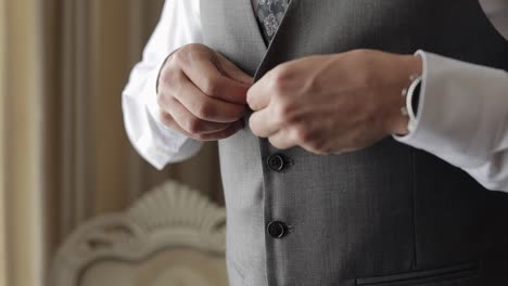 buttoning jacket with hands close up, man in suit fastens buttons on his jacket preparing to go out