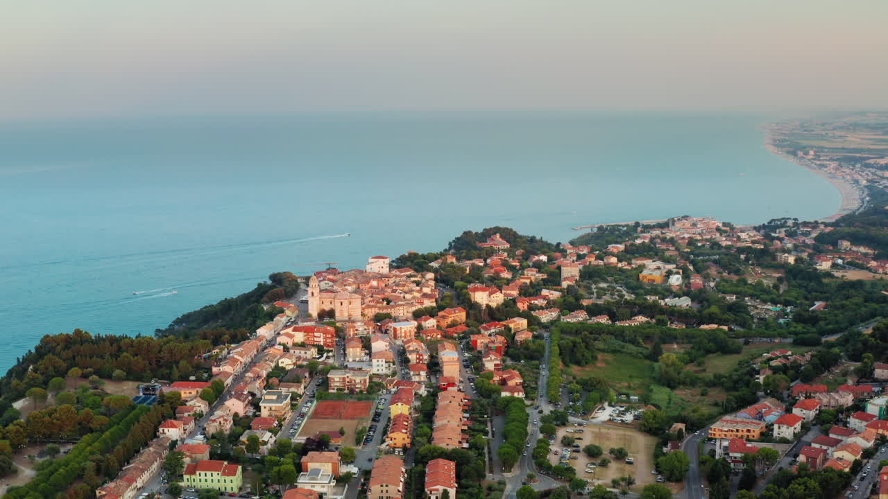 volando sobre una pequeña ciudad histórica en marche, italia en lo alto del acantilado sobre el mar adriático al atardecer