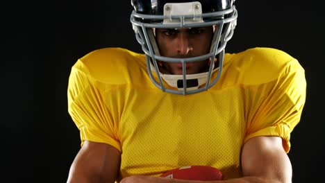 american football player holding ball against black background 4k