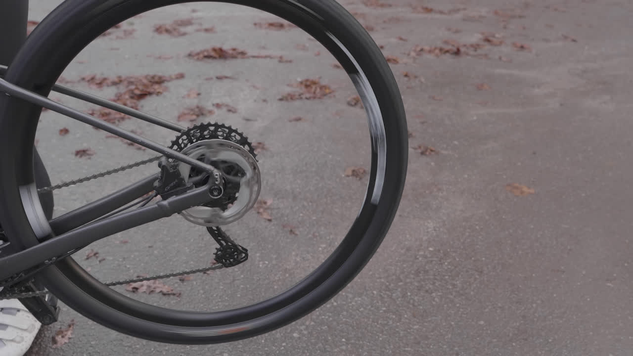 Primo piano della ruota posteriore e del pacco pignoni di una bicicletta che girano su pavimentazione esterna.