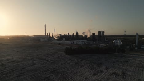 Toma-De-Drone-De-Planta-De-Energía-Funcionando-Con-Puesta-De-Sol-En-Segundo-Plano