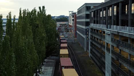 Tilting-up-shot-of-an-old-cargo-train-moving-down-the-track-in-Seattle,-Washington-during-dusk-on-a-cloudy-overcast-day