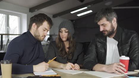 team of young professionals having a meeting in a creative office. taking notes and brainstorming. business discussion. coffee cups on the table. shot in 4k