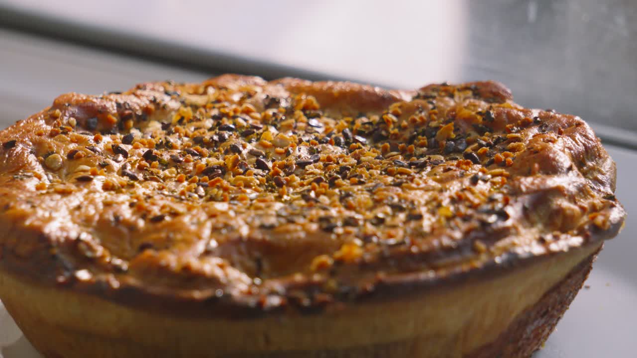 Close Up Slow Pan Across Rustic Chicken and Mushroom Pie with Seeds Dressed Across the Top. Poultry Meat Based Dish Cooked in Hot Oven in Kitchen