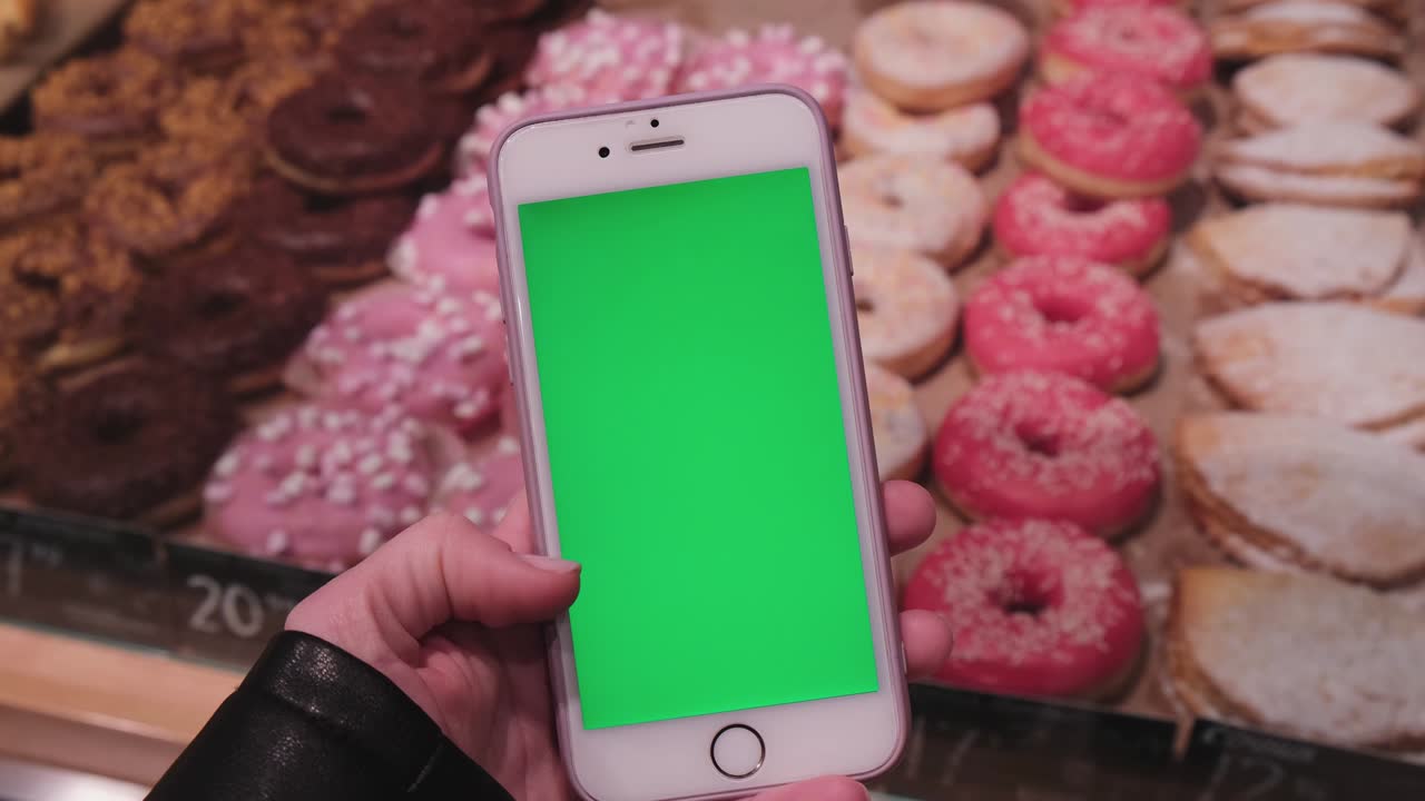 llave de croma. primer plano de una mujer sosteniendo un teléfono inteligente con pantalla verde en una tienda de comestibles. centro comercial. tienda departamental. centro comerciales. compras en línea