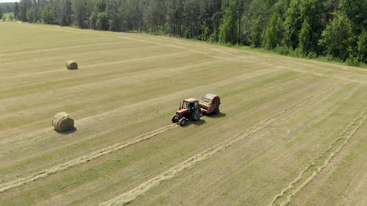 공중 에서: 트랙터 를 타고 있는 농부 가 뜨거운 빛 의 날씨 에 잔디 에서 풀 어리 를 어 싸고 있다